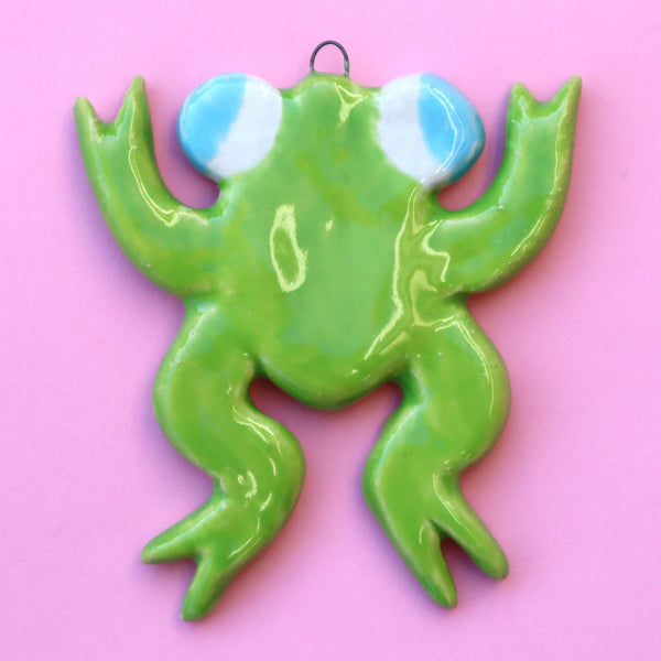 Ceramic Frog Holiday Ornament on a Pink Background made by Eva Stalinski 2022
