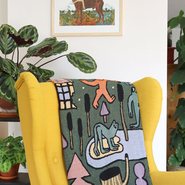 Woven Fairytale Forest Throw Blanket by Eva Stalinski 2021 in situ on yellow ikea strandmon chair