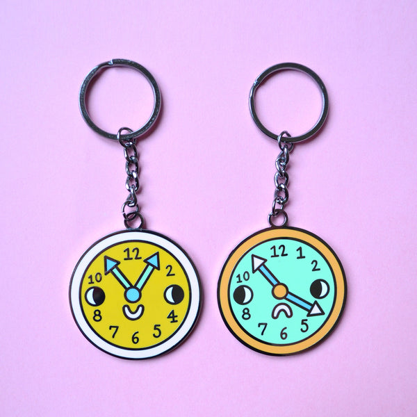 Double Sided Hard Enamel Vintage Looking Analog Clock Key Chain by Illustrator and Print Maker Eva Stalinski 2020 Two Clocks Side by Side on Pink Background